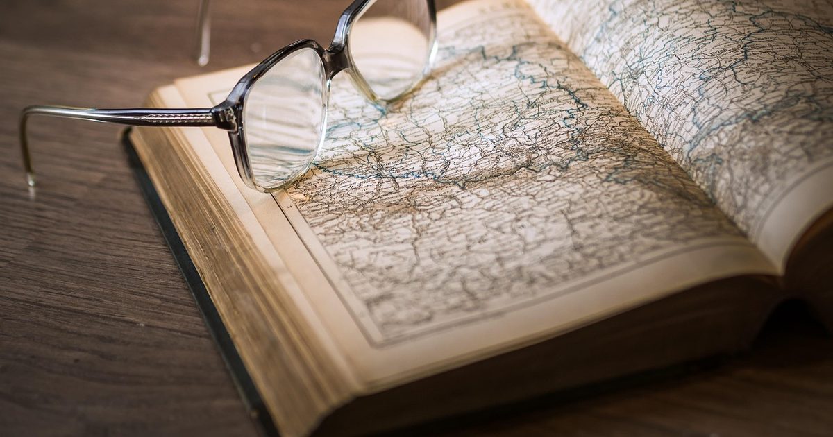 An open atlas and a pair of glasses